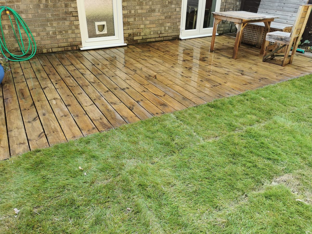 After: Tired decking and old slabs to restored decking and new turf